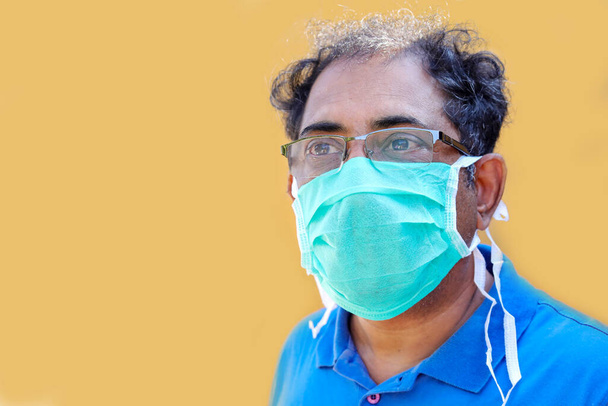 lähikuva Etelä-Aasian mies yllään naamio suojella virusta ilmasta keltaisella pohjalla
 - Valokuva, kuva