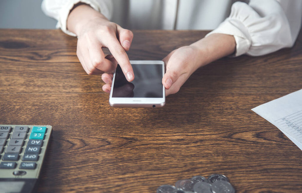 женщина рука смартфон с монетами и калькулятор на столе
 - Фото, изображение