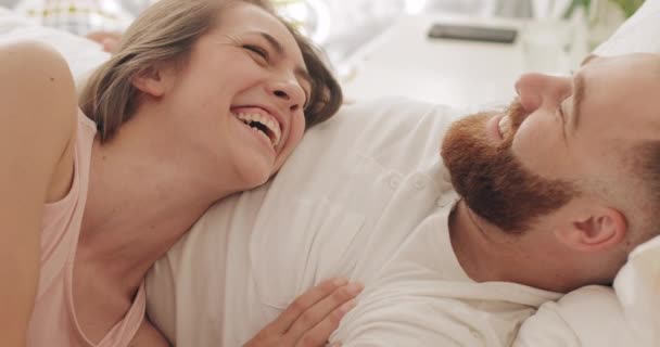 Close up view of happy couple lying on bed in early morning, talking andlaughing. Beautiful woman and her handsome husband having good time.Concept of family and relationship. - Metraje, vídeo