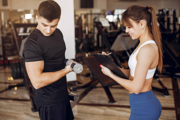 A beautiful sports couple is engaged in a gym - Photo, image