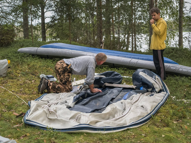 Reparación de kayak después de rafting. Punto de descanso en la isla. Vacaciones extremas activas en Karelia. Rafting en lagos y ríos del norte
 - Foto, Imagen