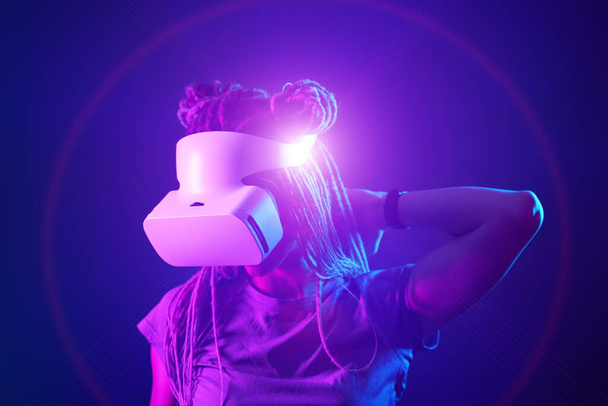 Kobieta używa gogli wirtualnej rzeczywistości. Neon światło studio portret. - Zdjęcie, obraz