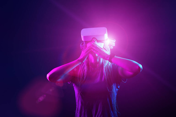 A nő virtuális valóság headsetet használ. Neon light stúdió portré. - Fotó, kép