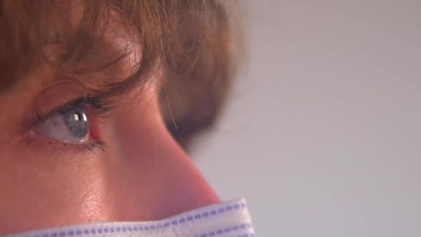 Nahaufnahme einer kaukasischen Frau, die blinzelt, während sie eine schützende Gesichtsmaske trägt - Filmmaterial, Video