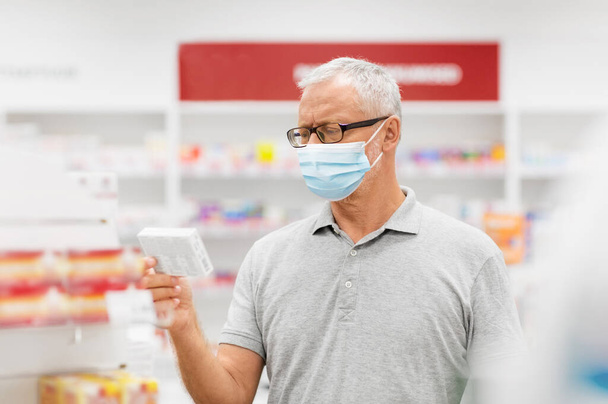 пожилой человек в медицинской маске с лекарством в аптеке
 - Фото, изображение