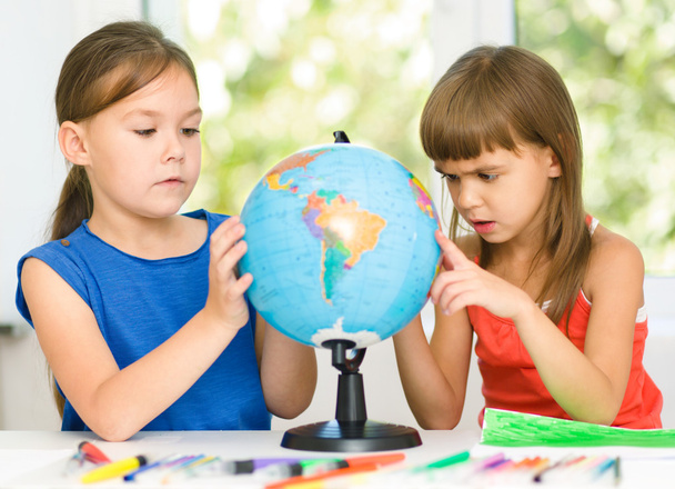 Little girls are examining globe - Foto, imagen
