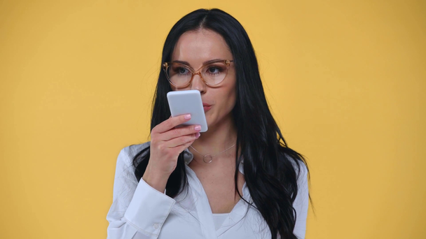 Femme d'affaires utilisant haut-parleur tout en parlant sur smartphone isolé sur jaune
 - Séquence, vidéo