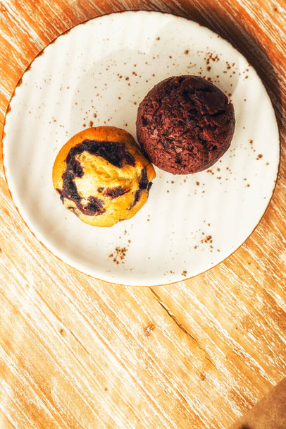 Δύο μεγάλα ζουμερά νόστιμα muffins σε διαφορετικές γεύσεις. - Φωτογραφία, εικόνα