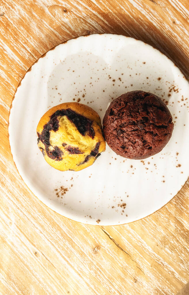 Δύο μεγάλα ζουμερά νόστιμα muffins σε διαφορετικές γεύσεις. - Φωτογραφία, εικόνα