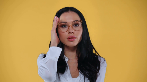 Geschokte zakenvrouw in bril kijkend naar camera geïsoleerd op geel - Video