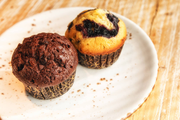 Twee grote sappige smakelijke muffins in verschillende smaken. - Foto, afbeelding