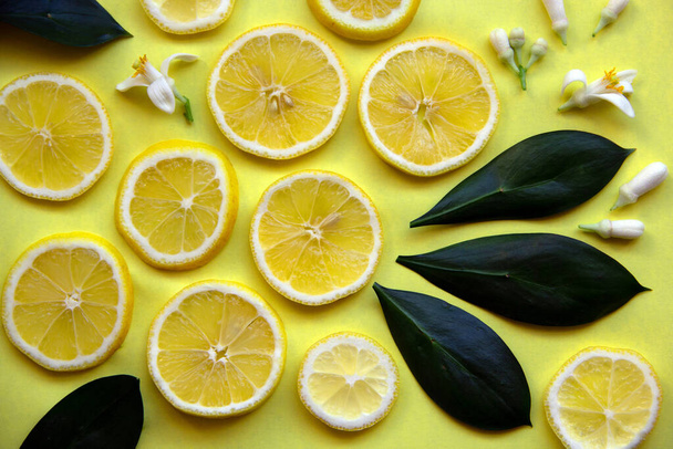 Padrão de layout criativo com fatias de limão amarelo, folhas e flores de limoeiro em um fundo amarelo. Conceito mínimo de verão. Deitado. Espaço de cópia, cartão de papel
. - Foto, Imagem