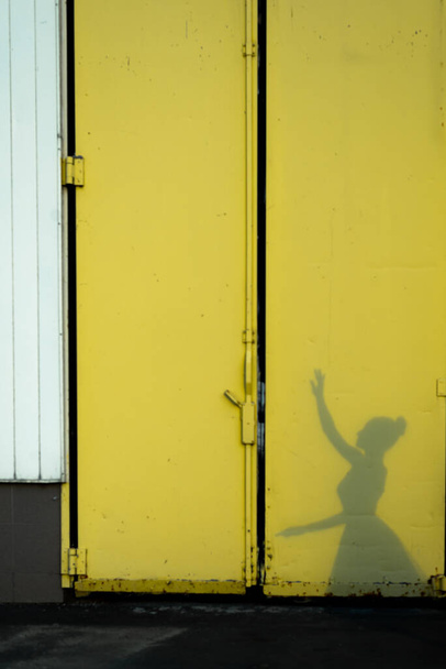 Silhouet van een ballerina op de gele poort. Geen focus. Shadow van een ballerina - Foto, afbeelding
