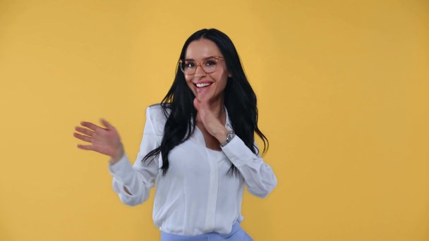 Piękna bizneswoman tańczy i uśmiecha się do kamery odizolowanej na żółto - Materiał filmowy, wideo