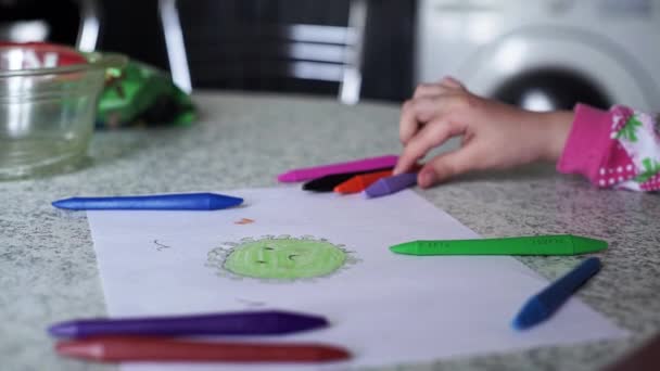 Une petite fille dessine le coronavirus sur papier blanc avec des crayons de couleur. Gros plan des mains de la fille avec des crayons de couleur. Covid-19. Padnémique. Isolement - Séquence, vidéo