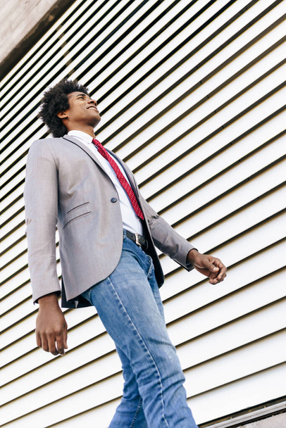 Black confident Businessman wearing suit walking in urban background. Man with afro hair. - Fotó, kép