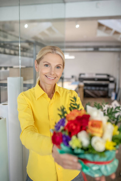 Blonde woman receiving flowers and feeling happy - Photo, Image