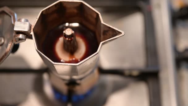 Detailní záběr výlevky: káva začne vytékat a plnit kávovar a pak z ní vytéká pěna. V rozmazaném pozadí můžete vidět modrý plamen hořících kamen - Záběry, video