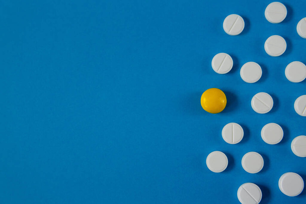léky a zdraví, bílé a žluté pilulky na modrém pozadí shora - Fotografie, Obrázek