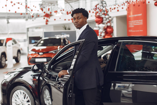 Handsome and elegant black man in a car salon - 写真・画像