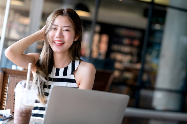 életmód vonzó ázsiai nő alkalmi ruha relax munka laptop okostelefon szabadúszó karrier mosoly boldogsággal és magabiztos a kávézó elmosódott háttér - Fotó, kép