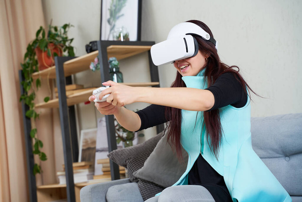 仮想現実のヘッドセットとゲームパッドを持つ女性がゲームをプレイしている. - 写真・画像