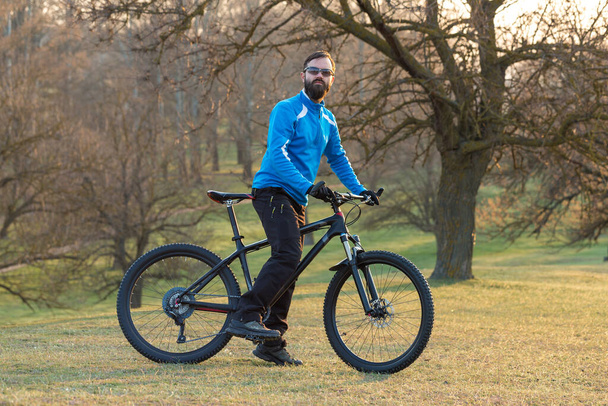 Cyclist in pants and fleece jacket on a modern carbon hardtail bike with an air suspension fork. The guy on the top of the hill rides a bike. - Photo, Image