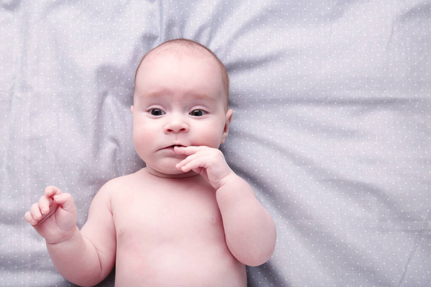 Cute baby in diaper lying with her fingers in mouth - Foto, Imagen