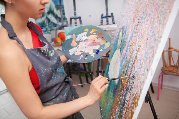 Обрезанный снимок молодой женщины, наслаждающейся картиной в художественном классе, держащей палитру масляной краской
 - Фото, изображение