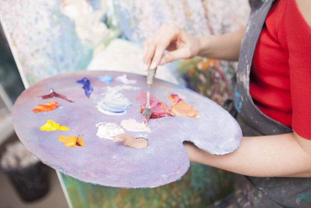 Close up of a palette where female artist mixing oil paint. Unrecognizable woman working at art studio - 写真・画像