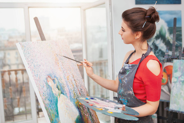 Charming young woman enjoying painting at her workshop. Creativity, relaxation concept - 写真・画像