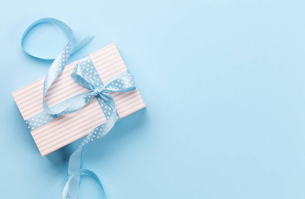 Grußkarte mit pastellfarbenem Geschenkkarton auf blauem Hintergrund. Draufsicht flach liegend mit Platz für Ihre Grüße - Foto, Bild