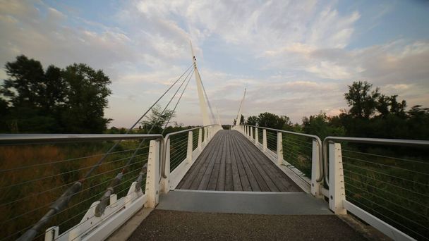 bridge over the river secchia in sassuolo modena with wooden walkway at sunset - Foto, imagen