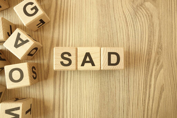 Słowo smutne z drewnianych klocków na biurku - Zdjęcie, obraz