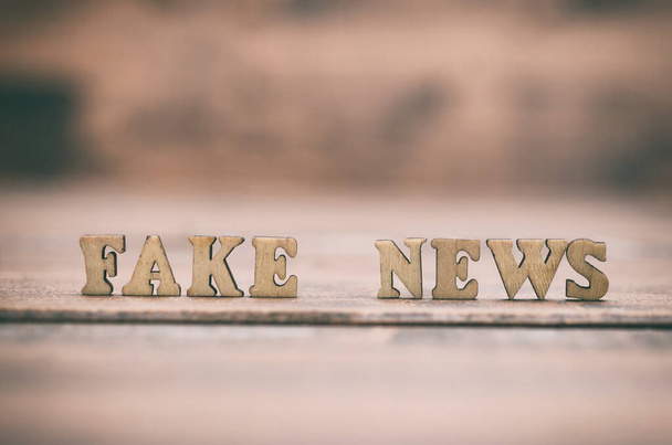 Fake news wooden letters on a wooden background. Fake news as a form of news consisting of deliberate disinformation or hoaxes spread via traditional news media (print and broadcast) - Foto, afbeelding