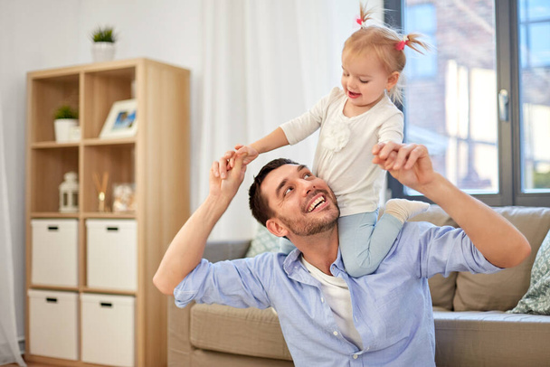 father riding little baby daughter on neck at home - Foto, imagen