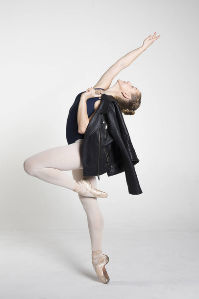 Młoda baletnica ćwicząca ruchy baletowe z kurtką w rękach w studio - Zdjęcie, obraz