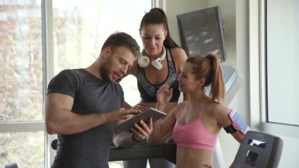 Junge Frauen diskutieren mit Fitnesstrainerin über Trainingsfortschritte auf digitalem Tablet - Filmmaterial, Video