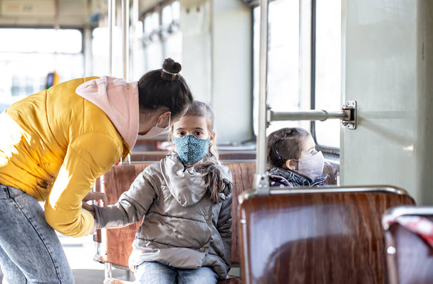 Una madre con dos hijos en el transporte público, con máscaras. durante una pandemia. Coronavirus
. - Foto, imagen
