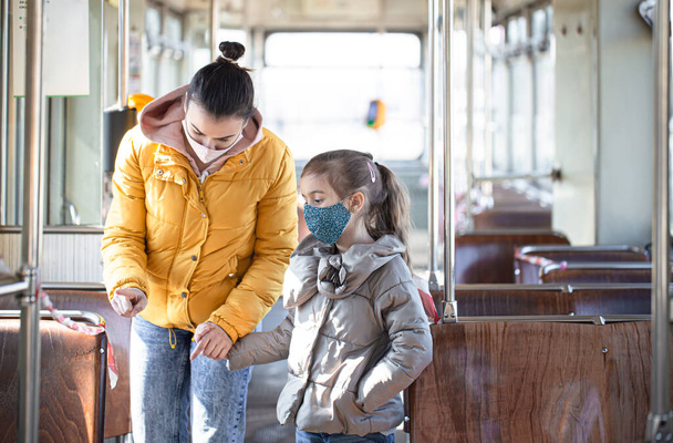 Eine Mutter mit einem Kind in einem leeren öffentlichen Verkehrsmittel, die während einer Pandemie Masken trägt. Coronavirus. - Foto, Bild