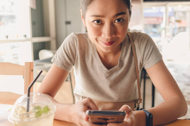 Happy woman is using smartphone in the coffee cafe. - Zdjęcie, obraz