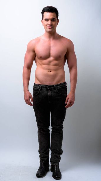 Studio shot of young handsome muscular man shirtless against white background - Zdjęcie, obraz