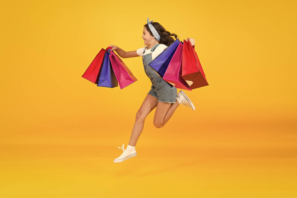 energetic child jump with heavy bags. holiday gifts in packages. cyber monday. hurry up its total sale. Kids fashion. Sales and discounts. happy small girl after successful shopping. Time to shop - Valokuva, kuva