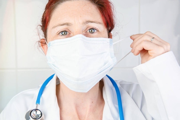 Close-up portrait of a nurse or doctor adjusting her protective surgical mask - Foto, afbeelding