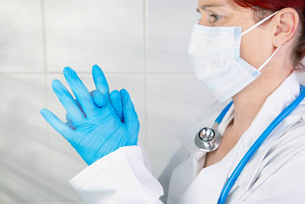 Side view of a nurse or doctor putting on her surgical gloves to protect herself - Фото, изображение