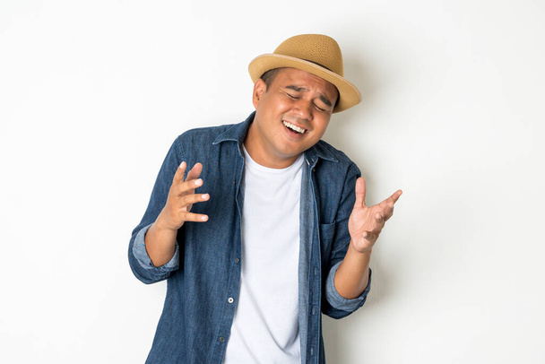 Азиатские мужчины в возрасте около 30 лет носят шляпы и джинсы. Стоять и радостно смеяться
 - Фото, изображение
