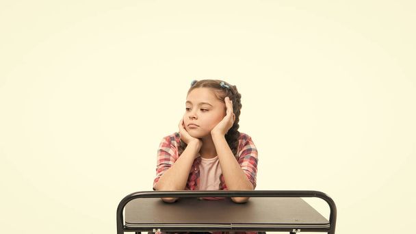 Student seems bored. Uninterested student isolated on white. Small girl student sitting at desk. Little student having lesson in school class - Foto, Imagen