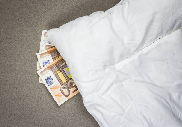 Esconder dinero debajo de la almohada. Billetes de banco de 50 euros bajo la almohada blanca
. - Foto, Imagen
