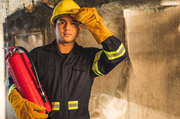 Молодий азіатський пожежник, пожежники використовують вогнегасне гасіння, яке горить у будівлі
. - Фото, зображення