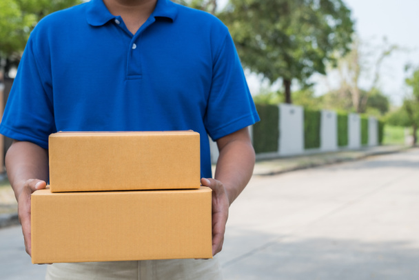 Blue Delivery man holding parcel cardboard box. - Φωτογραφία, εικόνα